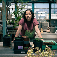 Woman stands in greenhouse with plants